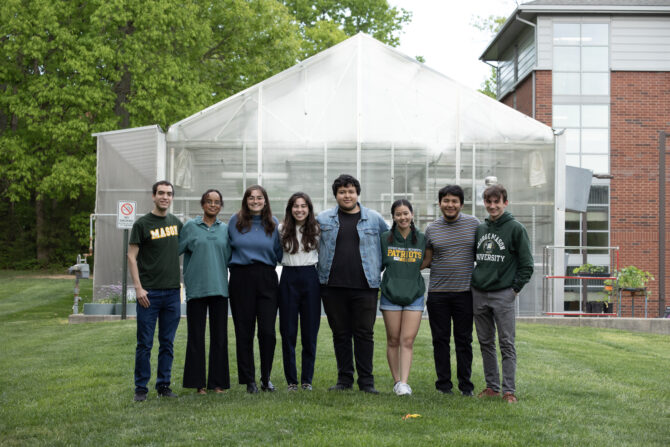 A group of 8 undergraduate students in front of Mason's hydroponic greenhouse.
