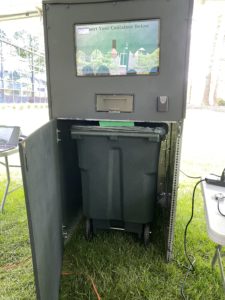 Reusable container kiosk with display screen and open door to show bin on the inside.
